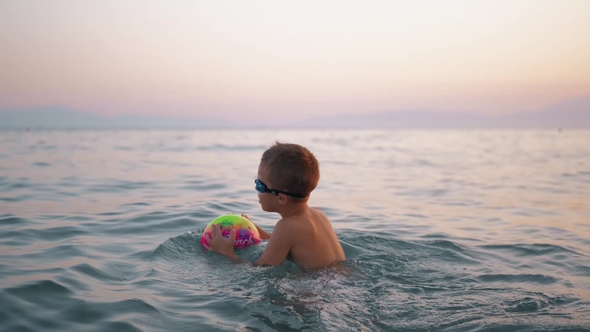 Child Taking Ball To Water and Then Floating on It in the Sea