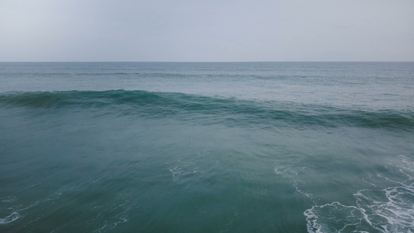 Aerial Drone Flyover Shot of Big Ocean Wave Crashing with White Foam in Breathtaking Dark Blue Open