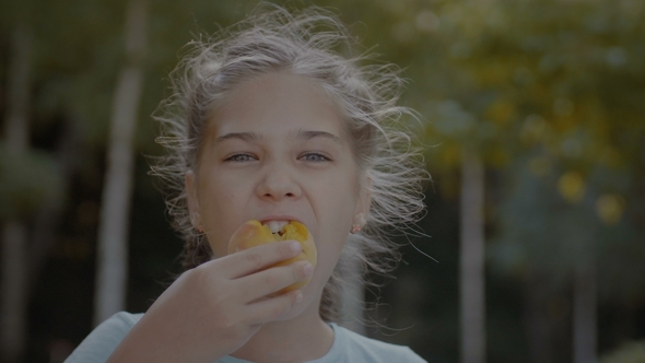 Smiling Cute Preteen Girl Eating Peach Outdoors