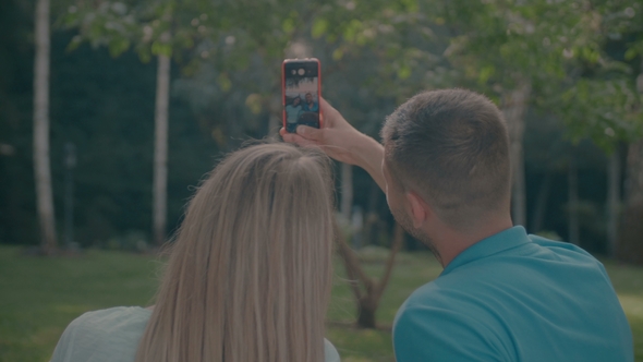 Smiling Couple with Cellphone Taking Selfie in Park
