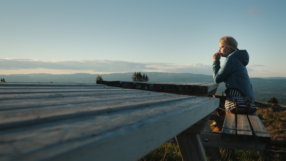 A Lonely Middle-aged Woman Sitting at a Table High in the Mountains Prays