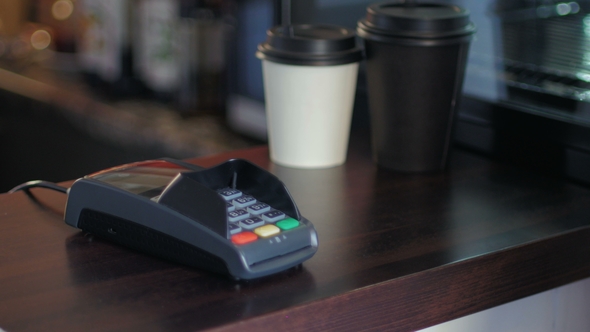 Young Man in Cafe Is Paying the Price By Using a Smart Phone and Terminal