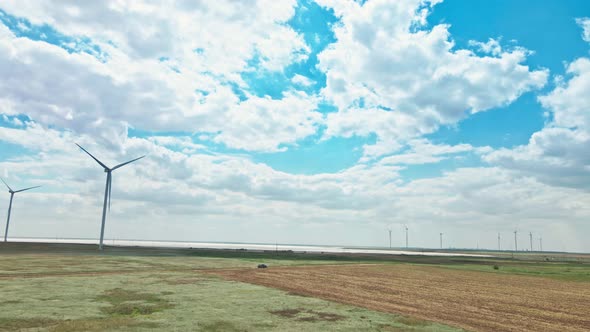 Car Moving By Rustic Road on Wind Electric Generators Background