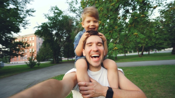 Happy Father Carrying His Smiling Son on Neck and Making Video Selfie