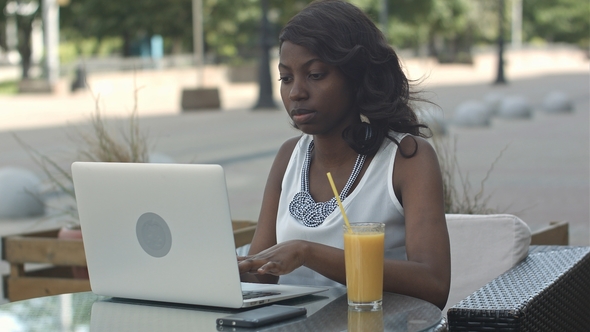 African American Woman Working on Laptop Outdoor and Drinking Juce