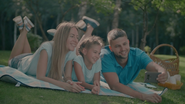 Family with Child Making Selfie on Blanket Outdoors