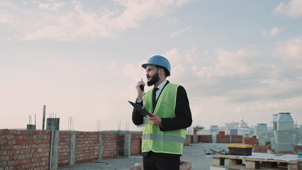 On Rooftop at Construction Site Businessman Wearing a Safety Helmet and High Visibility Vest