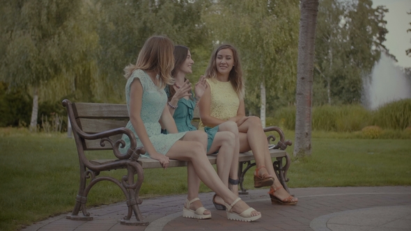 Pretty Women Sitting and Gossiping on Bench in Park