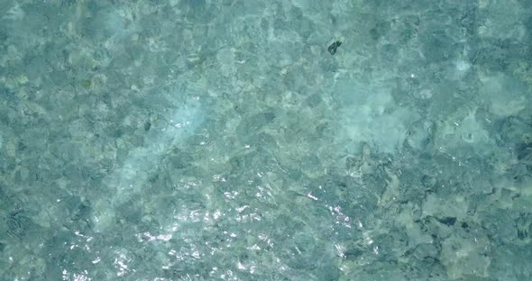 Wide angle aerial tourism shot of a white sandy paradise beach and turquoise sea background in colou