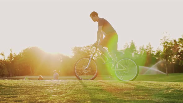 Cyclist Rides on the Lawn at Sunset