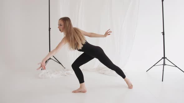 Sensual Young Girl is Engaged in Stretching with Elements of Classical Dance Against the Background