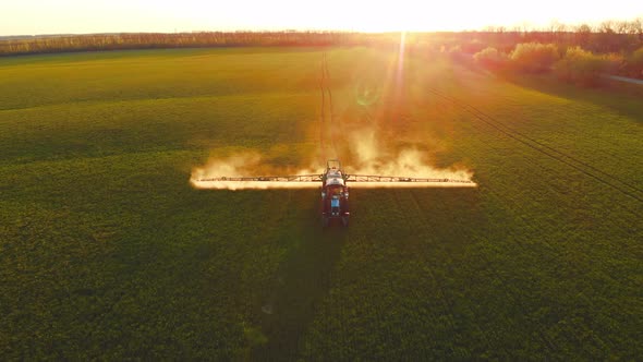 Aerial Video of Tractor Spraying Soil and Young Crop in Springtime in Field