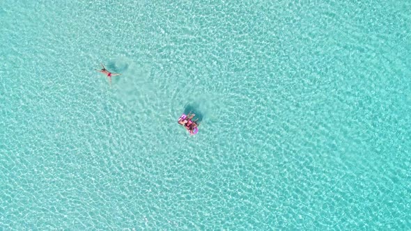 Attractive woman swimming next to the children on an inflatable mattress