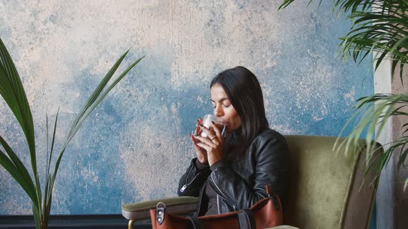 Young Stylish Woman Drinking Coffee in Cafe