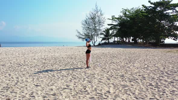 Pretty happy ladies on photoshoot by the sea on beach on sunny blue and white sand background 4K