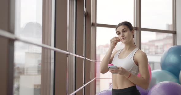 Beautiful Young Sportswoman with Earphones Listening to Music