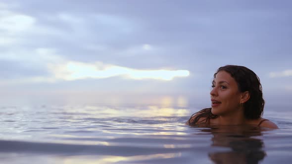 Female Model Smiling Dipped in Water With Backdrop of the Majestic Dusk Skies