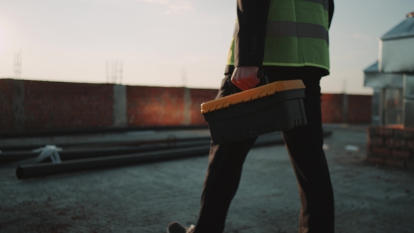 Construction Site Builder or Engineer Walking To See Amazing Sunset Holding a Instrument Bag