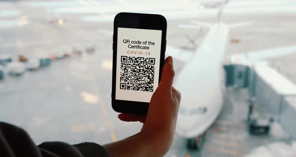 Passenger Shows Fake and Nonactive QR Code in Airport on Screen of Smartphone