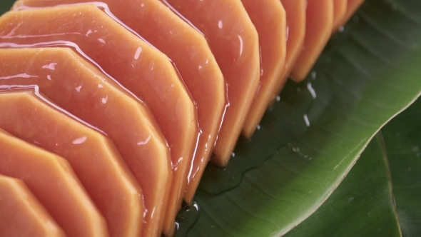 Pouring Syrup Onto Slices of Fresh Raw Exotic Tropical Thai Fruit Carica Papaya Rotating on Banana