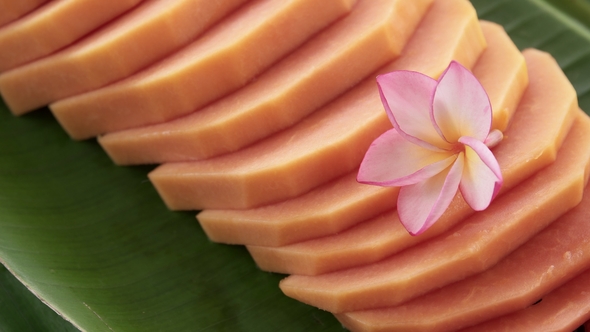 Slices of Fresh Raw Exotic Tropical Thai Fruit Carica Papaya Rotating on Banana Leaf