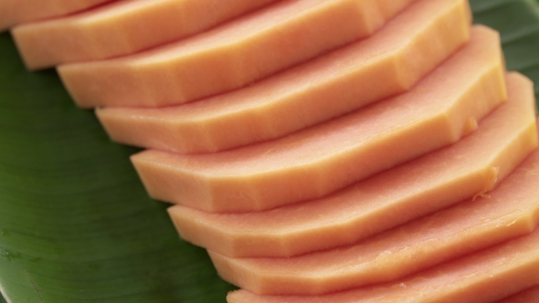 Slices of Fresh Raw Exotic Tropical Thai Fruit Carica Papaya Rotating on Banana Leaf