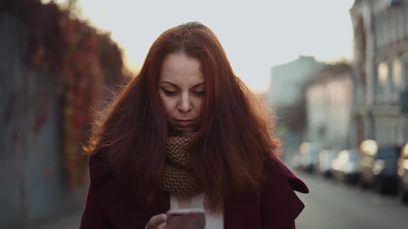 red-haired girl in the old town looks at the phone