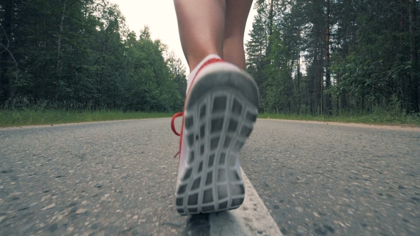 Female Feet in Sneakers Are Starting To Run in . Healthy Slim Young Sportswoman Running.