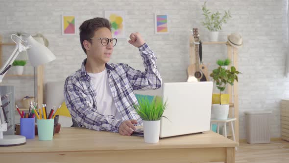 a Young Asian Man in Stylish Glasses Got a Win Rejoices and Dances Behind a Laptop in the Living