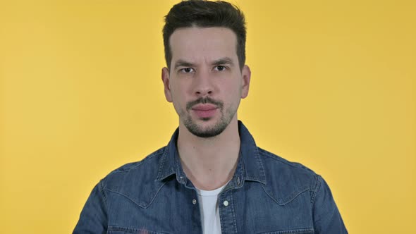Portrait of Attractive Young Man Saying No By Finger, Yellow Background