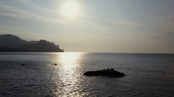 Flying Backward Over the Sea Surface with Rocks and Stones at Sunrise