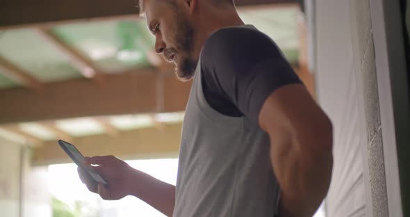 Young Adult Man Using Smartphone Tracking App During Fitness Sport Workout Stretching