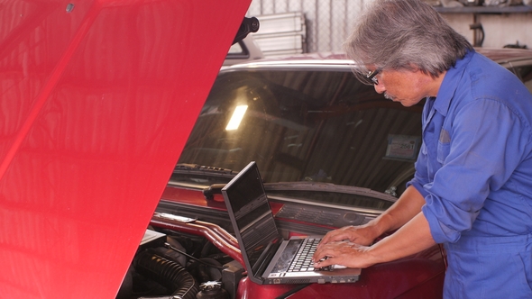 Mechanic Repairs the Damage Using the Pc Under the Hood in Car Service.