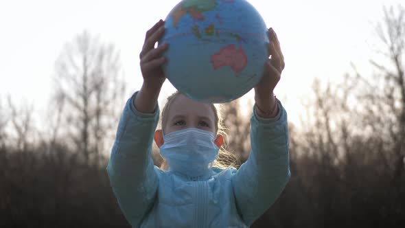 Sad Child Girl in Medical Mask Holding the Globe.