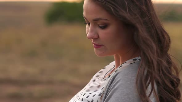 Portrait of a Young Girl with Long Dark Flowing Hair in a Field at Sunset