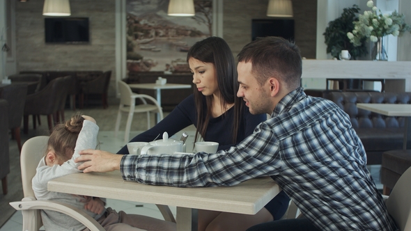 Ordinary Family of Three with Little Daughter in Cafe. Father and Mother Reassuring Their Child