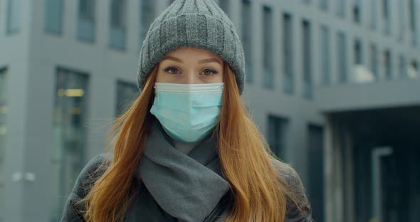 Close Up Portrait of a Beautiful Redhead Young Woman in a Hat Wearing Protective Medical Face Mask