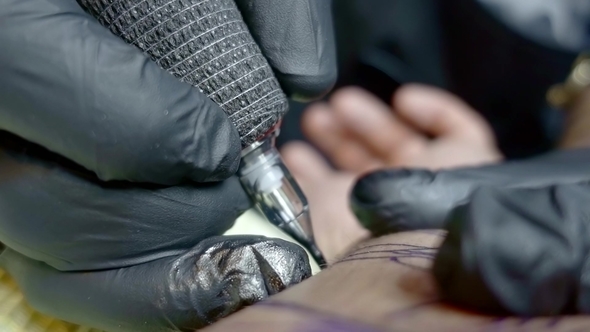 Shot of a Tattoo Master Working with a Tattoo Machine in the Studio.