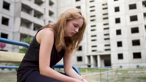 Nervous Girl Is Sitting Near High Building