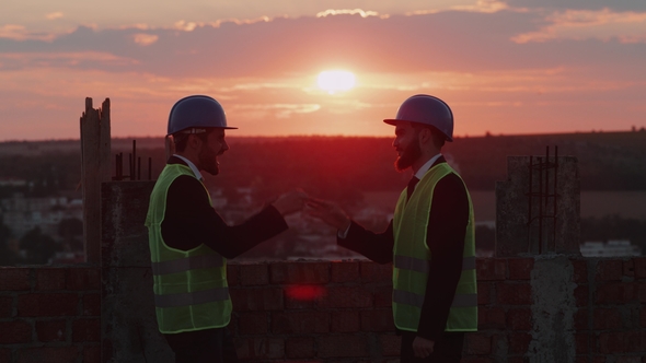Two Businessman Have a Great Time Together at Construction Site on Rooftop Playin with Hands Smiling