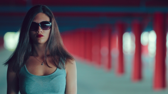 Pretty Girl in Sunglasses Looks at the Camera and Goes Forward in the Underground Parking