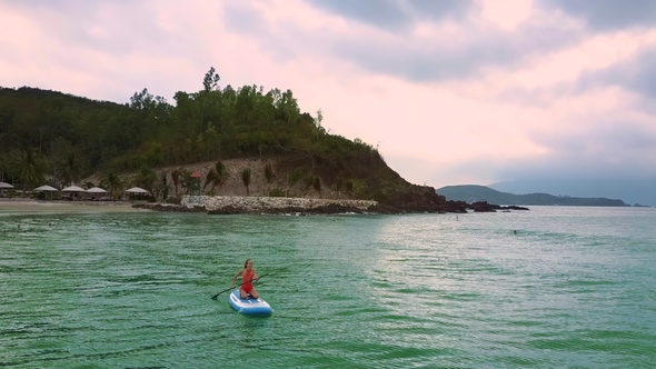 Girl Swims Sitting on Paddleboard Turning From Beach To Ocean