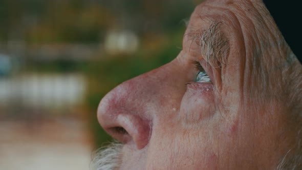 elderly senior face opening eyes in meditation and contemplation loooking up at the sky with hope an