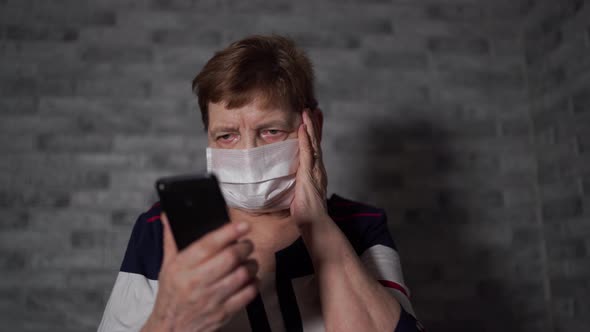 An Old Woman with a Medical Mask, Learns the News About Coronavirus From the Internet Using 