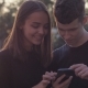 Couple Sharing Media in a Smart Phone in a Park with Buildings in the Background - VideoHive Item for Sale