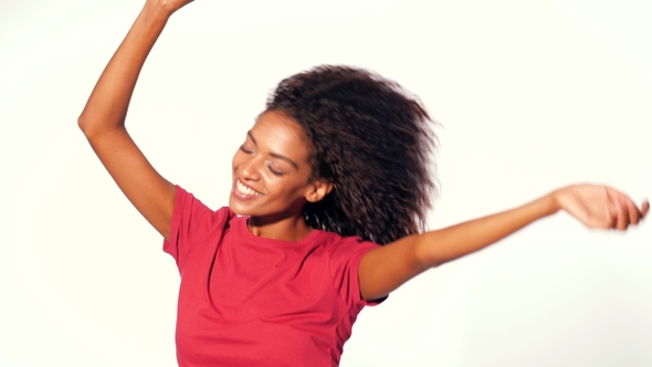 Young Attractive African American Woman in Red Top Enjoying Life and Dancing at White Background