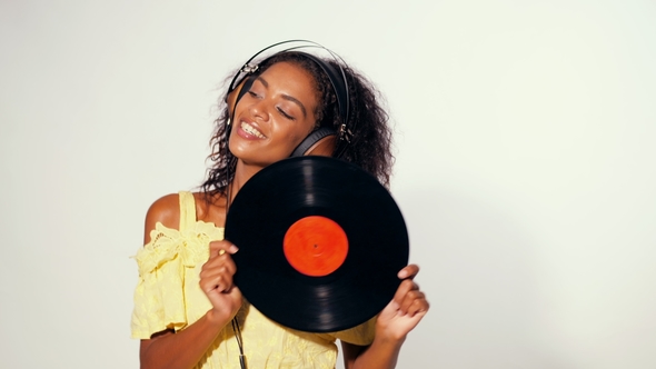 Young Beautiful African American Woman with Headphones in Yellow Dress Enjoying and Dancing