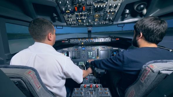 Two Men Are Sitting in a Cockpit of a Flight Simulator