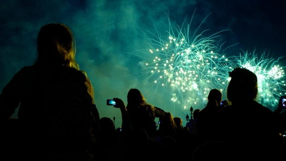 Crowd of People Looks at the Fireworks at Night. Multicolored Pyrotechnic Show on the Holiday