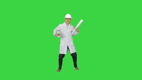 Happy Young Engineer Dances with Blueprints in a Funny Way on a Green Screen, Chroma Key.
